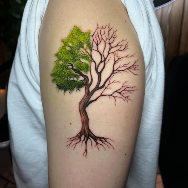 Colorful tree tattoo with roots on arm.
