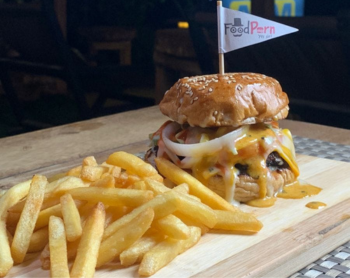Cheeseburger with melted cheese and onions served with crispy french fries on a wooden board.